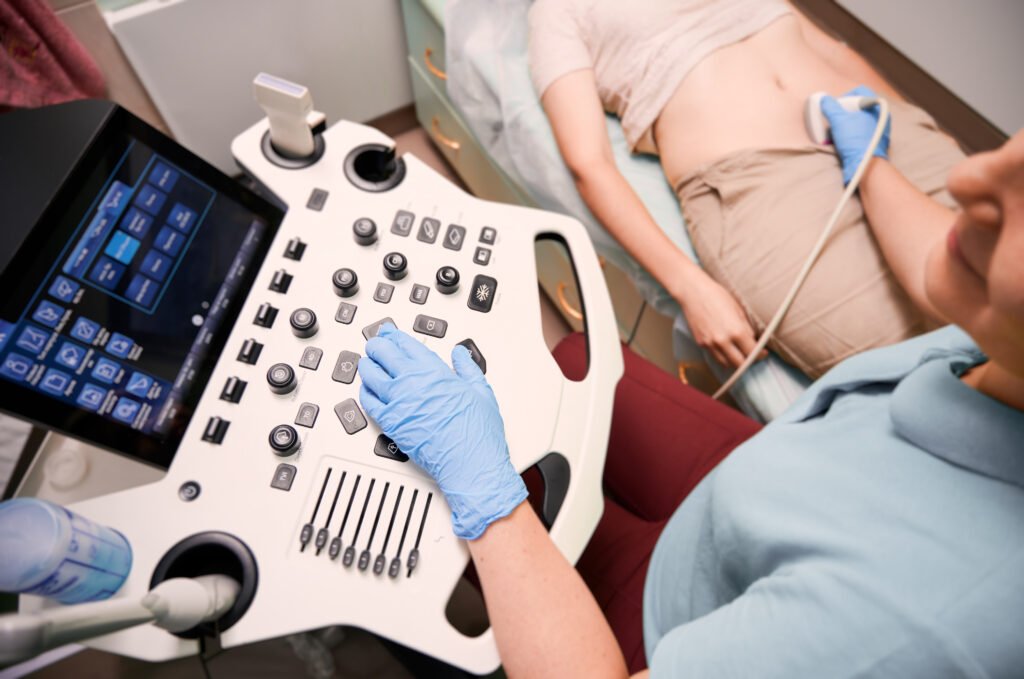 Gloved healthcare professional conducting an abdominal ultrasound scan using advanced diagnostic equipment at Kaiwalya Hospital, the best hospital in Indore on Khandwa Road.